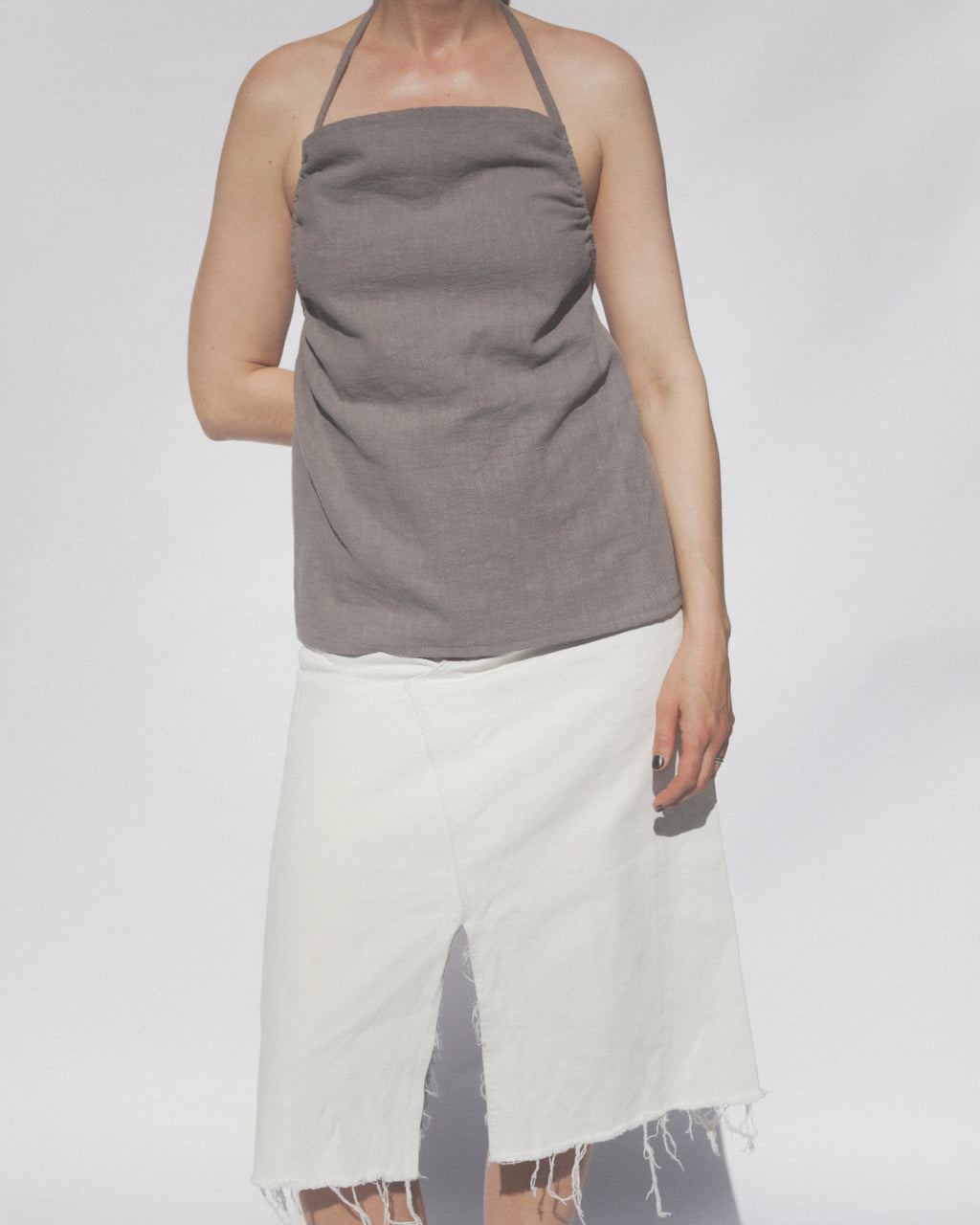 Model wearing a gray halter top and white skirt on a plain background