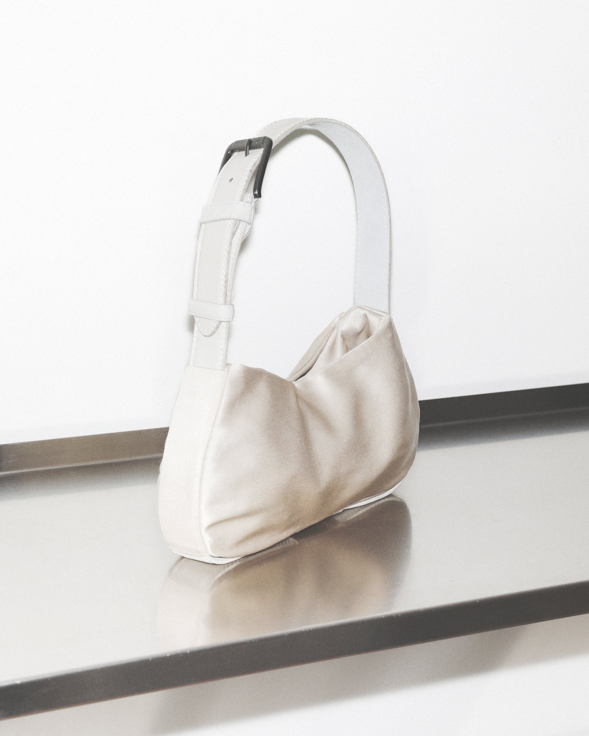 White handbag on a reflective surface with a white background