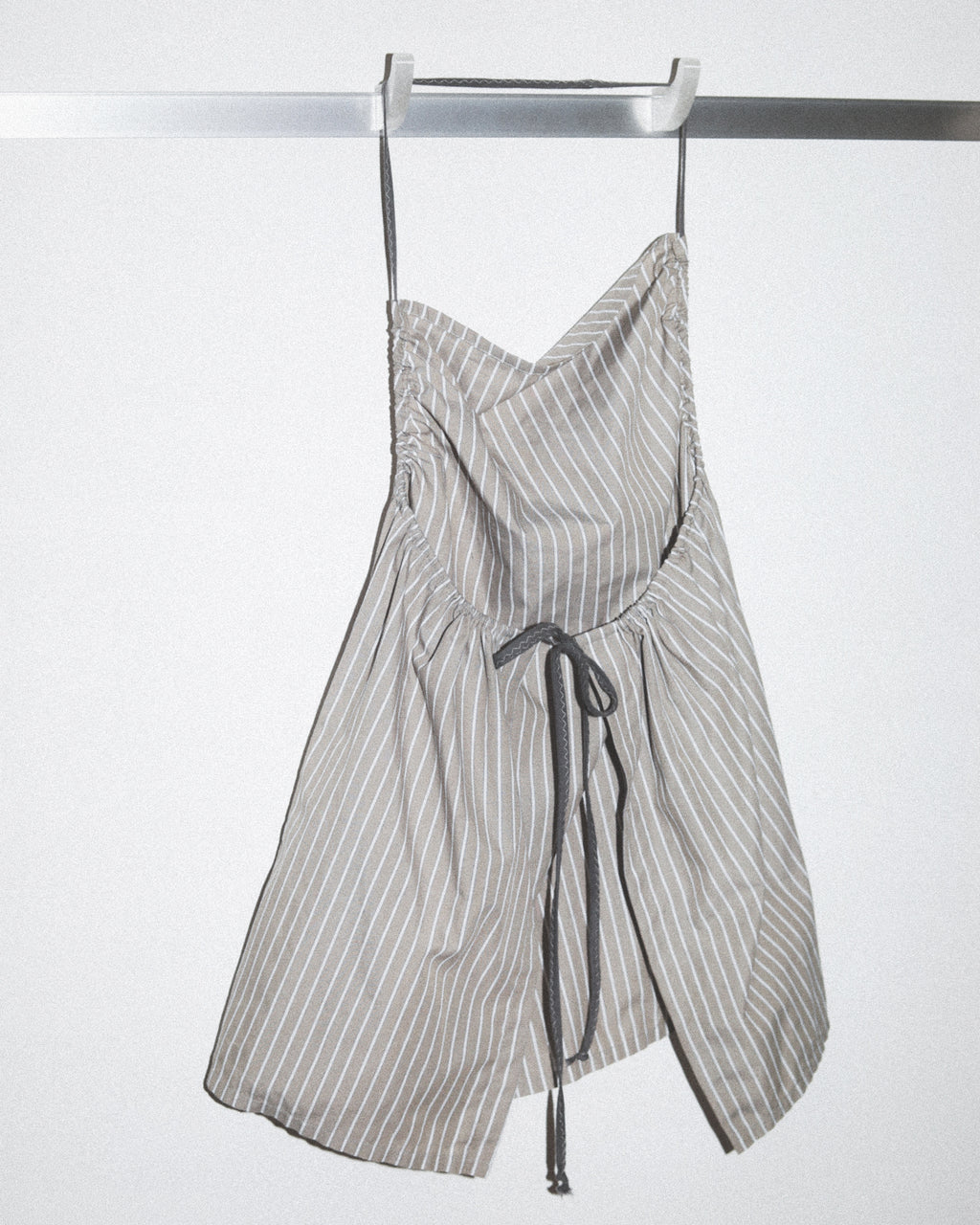 Striped top hanging on a rack against a white background