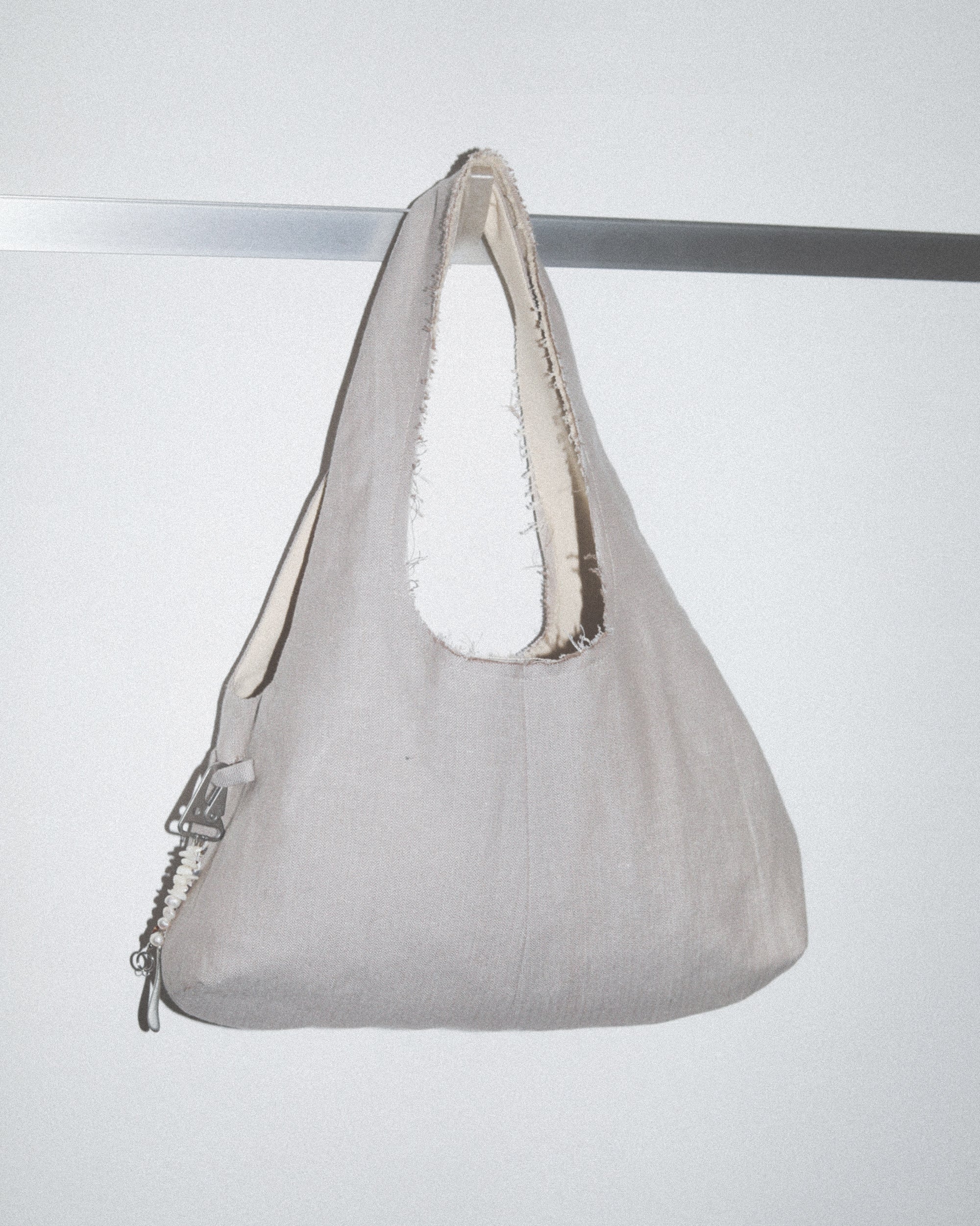 Gray handbag with white interior lining on a light gray background
